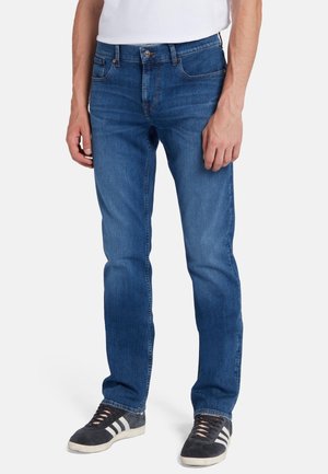 Blauwe denim jeans met een rechte pasvorm, voorzien van vijf zakken, een knoopsluiting en subtiele stikseldetails. Gecombineerd met donkere sneakers.