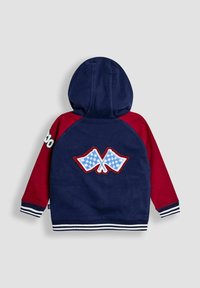 Hanorac cu glugă, având blocuri de culoare albastre și roșii, steaguri în carouri brodate pe spate și manșete și tiv cu dungi.