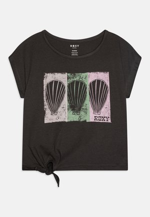 Camiseta negra de manga corta con un dobladillo anudado, que presenta un gráfico de tres globos aerostáticos en cajas verdes, rosas y blancas con un aspecto desgastado.