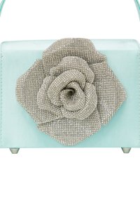 Miętowa torebka z teksturowanym akcentem w postaci srebrnego kwiatu z cyrkoniami z przodu, o strukturalnym designie i metalowych nóżkach.