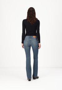 Flared blue denim jeans, mid-rise, with a five-pocket design and leather brand patch at the back. Smooth texture and fitted silhouette.