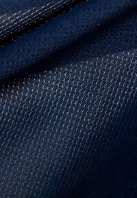 Mörkblått tyg med en texturerad yta som har en fin, mönstrad väv. Ljuset reflekteras subtilt för att framhäva dess djup och detalj.