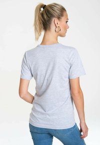Gray short-sleeve t-shirt with a rounded neckline, smooth cotton blend fabric, and a fitted design. Worn with blue jeans.