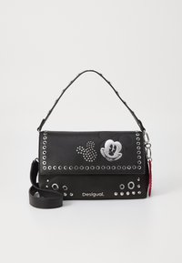 Sac en simili cuir noir avec des clous en argent, un graphique de Mickey Mouse, et une bandoulière amovible. Nom de la marque "Desigual" à l'avant.