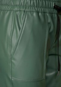 Vihreät nahkahousut, joissa on textured-pinta, joustava vyötärö, nyöri-yksityiskohta ja sivutaskut, joissa on kantatut reunat.