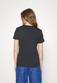 Černé bavlněné tričko s krátkými rukávy, kulatým výstřihem a hladkou texturou, spárované s modrými džíny.