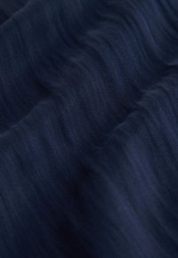 Tissu bleu foncé avec une texture côtelée fine et des plis doux créant un motif ondulé.