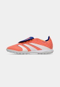 Zapato de fútbol naranja con rayas blancas, parte superior texturizada, acentos azules en la lengüeta y el talón, y una suela de goma para tracción.