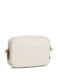 Τετράγωνη τσάντα σε κρεμ απόχρωση, κατασκευασμένη από λείο υλικό, με κλείσιμο με φερμουάρ και καφέ δερμάτινο λουράκι με χρυσές μεταλλικές λεπτομέρειες.