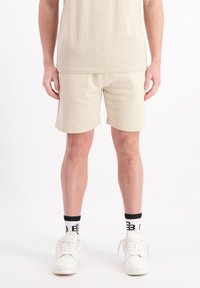 Beige katoenen shorts met een ontspannen pasvorm, met een gladde textuur en gestikte details, gecombineerd met witte sneakers en sokken met zwarte accenten.