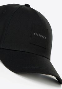 Schwarze Basecap aus glattem Stoff, ausgestattet mit einem quadratischen Patch, auf dem das Wort "WITTCHEN" in Silber gestickt ist, strukturierte Form mit einem gebogenen Schirm.
