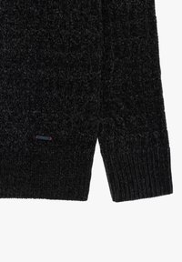 Maglione nero a trama con orlo a coste, dotato di una piccola etichetta con logo blu e rosso sul lato sinistro in basso.