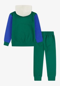 Conjunto de sweatshirts e calças de treino verdes, com mangas azuis e capuz em creme. Feito de tecido macio com punhos e cintura elásticos.