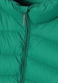 Zeleni puffer jakna sa visokim ovratnikom i prednjim zatvaračem. Materijal je sjajan, s quiltiranim dijelovima za izolaciju i teksturu.