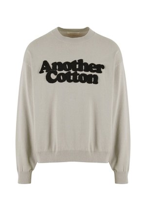 Šviesiai pilkas medvilninis megztinis su apvaliu kaklu, raukšlėtomis rankogaliais ir apačia. Priekyje yra juodos pakeltos ra letters "Another Cotton".