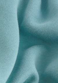 Tissu bleu clair avec une texture douce et lisse, présentant un motif de tricot fin. Le matériau semble léger et légèrement élastique.