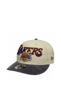 Casquette de baseball crème avec une visière en velours côtelé gris foncé. Présente un texte brodé "LAKERS" en violet et jaune, ainsi qu'un logo de basket à l'avant.