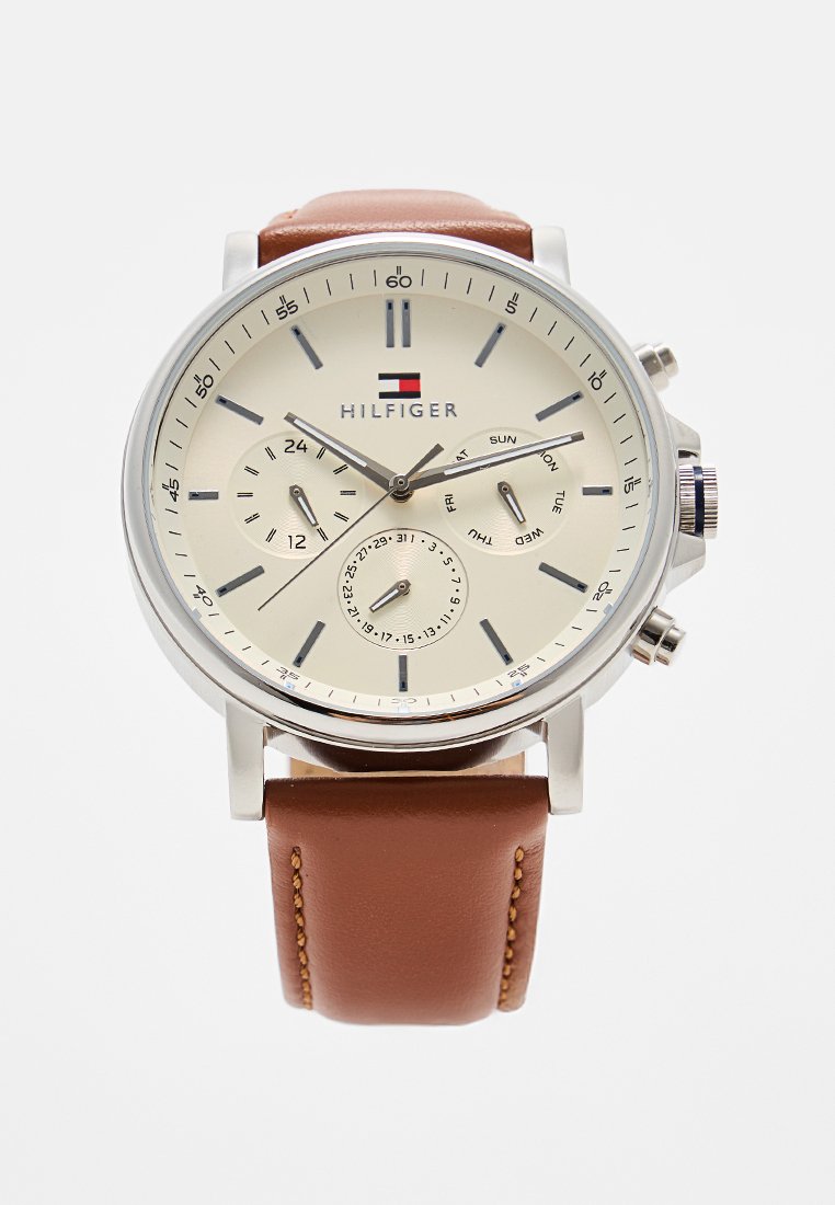 Silberfarbene Uhr mit Zifferblatt in Creme, braunem Lederarmband, Chronographenfunktion und Datumsanzeige. Logo ist oben in der Mitte angebracht.