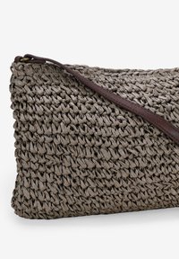 Borsa a tracolla grigia intrecciata con superficie texturizzata, dotata di una tracolla in pelle marrone e di forma rettangolare.