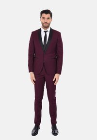 Abito bordeaux con rever in satin nero, camicia bianca e cravatta nera. Vestibilità su misura e taglio slim. Scarpe in pelle nere completano il look.