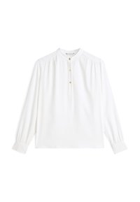Blusa blanca de manga larga con escote redondo, con tres botones dorados y pliegues sutiles en los hombros. Tejido liso y puños ajustados.