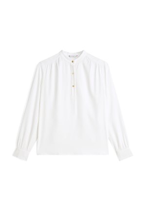 Hvid bluse med lange ærmer og rund halsudskæring, med tre gyldne knapper og fine plisséer på skuldrene. Glat stof og tætsiddende manchetter.