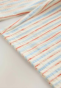 Večbarvno blago z teksturirano površino v krem, modrih in rdečih črtah. Blago je lahko in ima valovit vzorec.