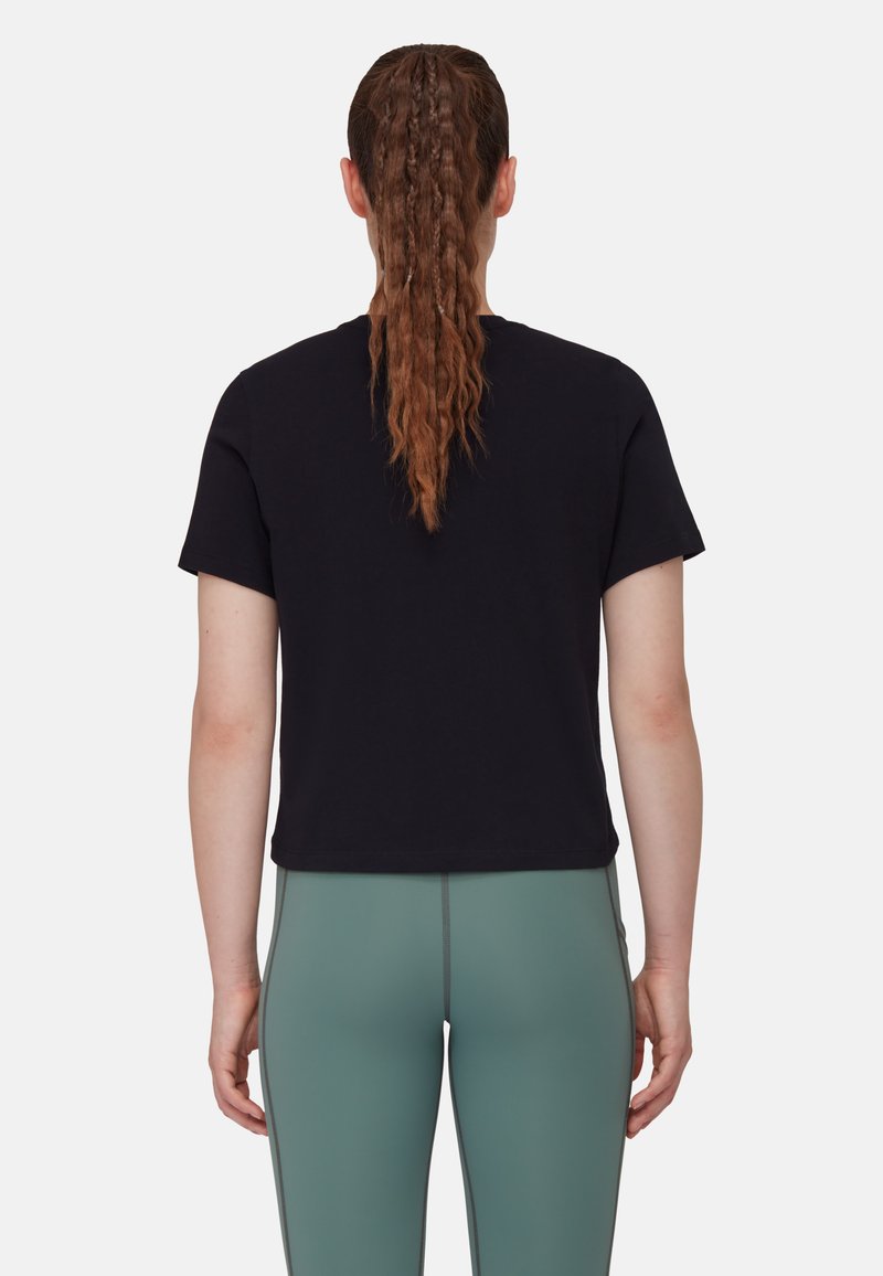Czarny t-shirt z krótkim rękawem z bawełny o luźnym kroju, połączony z miętowymi legginsami z kontrastowymi szwami, widocznymi z tyłu.