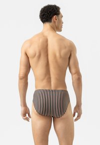 Zwarte zwemboxers voor mannen met verticale strepen in roze en crème. Rekbaar materiaal, nauwsluitend ontwerp, middelhoge taille en een gladde textuur.