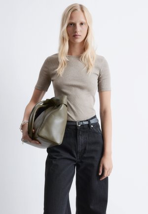 Top beige a coste con maniche corte abbinato a pantaloni in denim scuro a vita alta. Tieni in mano una borsa di pelle verde oliva strutturata con manici robusti.
