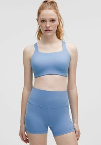 Ljusblå sport-bh med fyrkantig halsringning och breda band, i kombination med matchande högmidjade shorts. Slätt, elastiskt material.