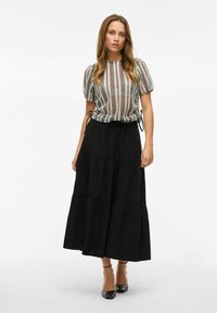 Juodas sluoksniuotas maksi sijonas su raišteliu juosmens, derinamas su raštuota trumpomis rankovėmis bluzone, turinčia vertikalias juosteles ir laisvą siluetą.