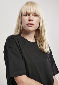 Čierne bavlnené tričko s voľným strihom, krátkymi rukávmi a okrúhlym výstrihom, s čistým šitím a hladkou textúrou.