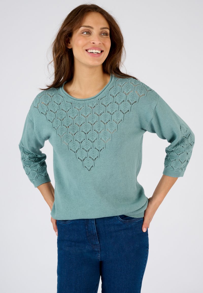 Suéter ligero de color azul claro con un patrón texturizado de encaje en forma de diamante en el pecho y mangas de tres cuartos, hecho de material de punto suave.