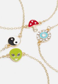Colar dourado com encantos de esmalte colorido: um cogumelo vermelho, yin-yang, rosto de alienígena verde e um pendente azul com pedras.
