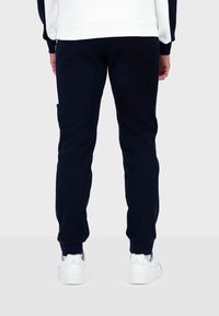 Marina blå sweatpants i mjukt material, med rak ben-design, ribbade cuffs och en sidficka. Bärs med vita sneakers.