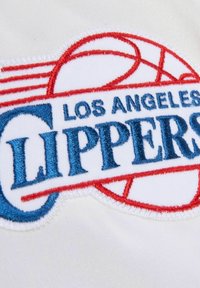 Logo brodé des "Los Angeles Clippers" en bleu et rouge sur un fond en tissu blanc, avec un design de basketball et des bords nets.
