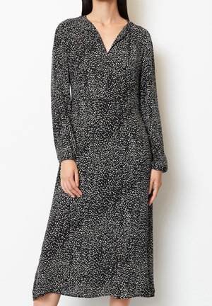 Robe midi noire avec un motif à pois blancs, décolleté en V, manches longues et coupe décontractée. Fabriquée en tissu léger avec une texture lisse.