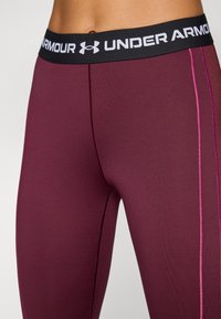 Under Armour leggings i dyp burgunder med svart linning. Har kontrastfarget rosa søm og et tettsittende, elastisk materiale.