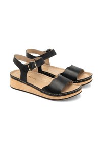 Czarne skórzane sandały z regulowanymi paskami na kostkę, wyściełaną wkładką oraz naturalną drewnianą podeszwą platformową. Posiadają wygięte paski oraz szczegóły szycia.