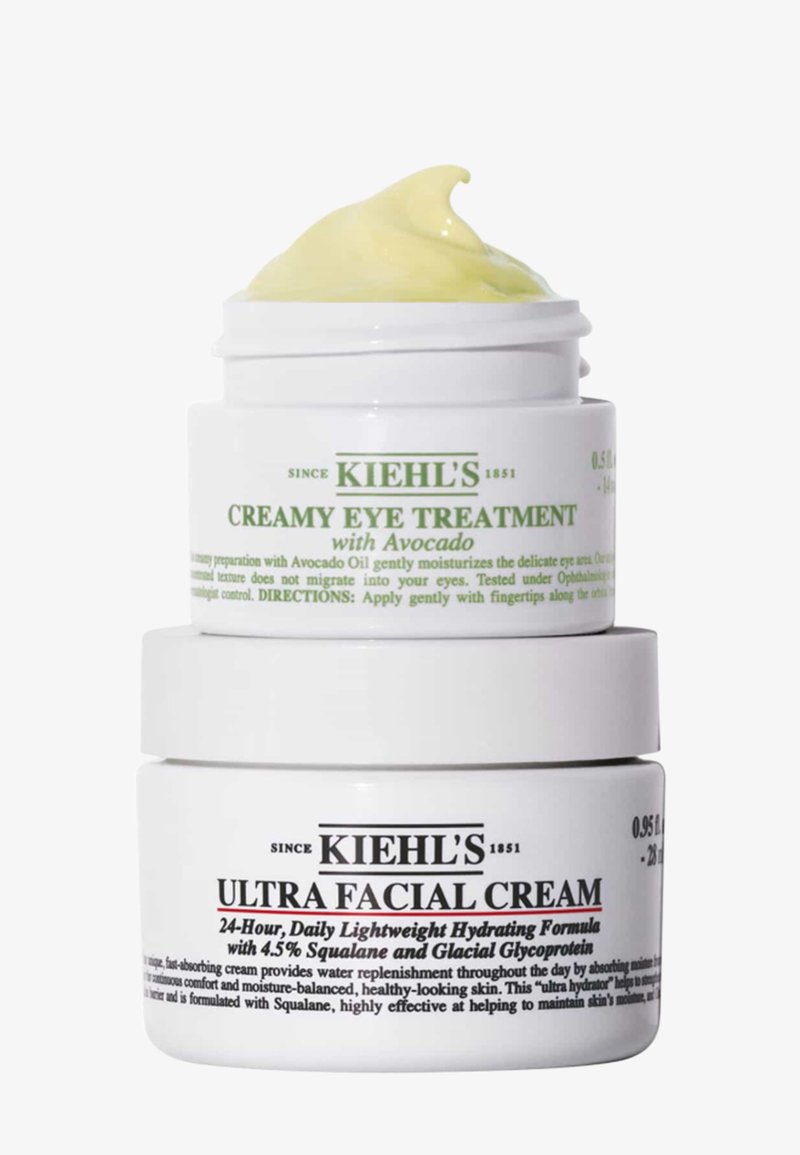 Il set di barattoli Kiehl's presenta un design in plastica bianca. Il barattolo superiore contiene una crema gialla; il barattolo inferiore, una crema bianca con testo e decorazioni nere.