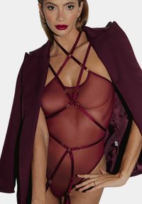 Burgundowa przezroczysta body z krzyżującymi się pasami i złotymi detalami, warstwowa pod dopasowaną kurtką. Gładka faktura, dopasowany krój.