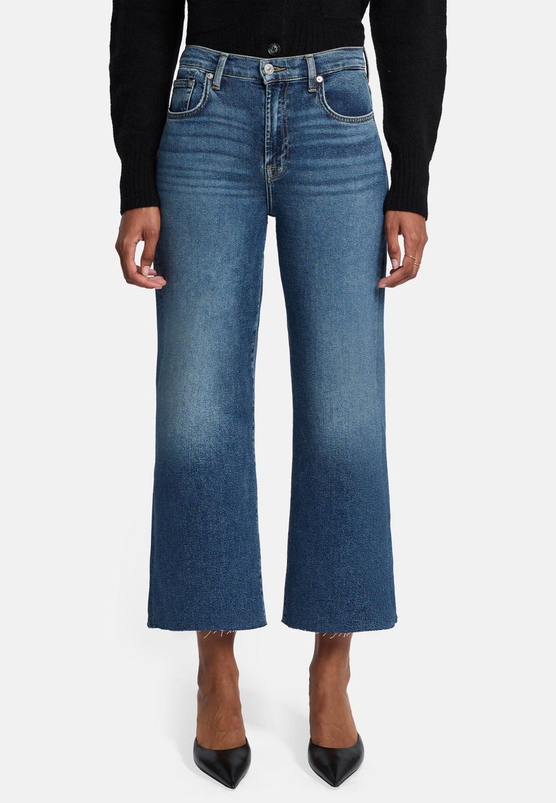 Culotte in denim blu chiaro con vita alta, sfumature delicate, orlo grezzo e design a cinque tasche. Abbinati a tacchi neri a punta.