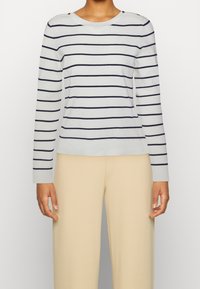 Randig långärmad tröja i ljusgrått och marinblått. Har en rund halsringning och knappr detaljer på axlarna. Mjuk textur, avslappnad passform.