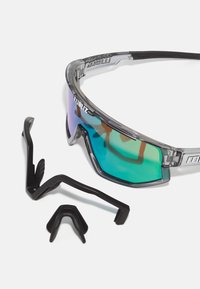 Sunglasses with gray translucent frame and green gradient lenses. Includes black adjustable nose piece and temple tips for customized fit.