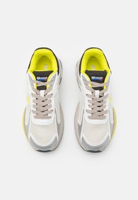Sneakers in mesh e materiali sintetici nei colori bianco, grigio e giallo. Caratterizzati da una tomaia testurizzata, colletto imbottito e suola in gomma, con lacci grigi.