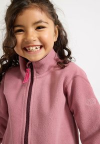 Giacca in fleece rosa con colletto alto, dotata di zip frontale e di un piccolo logo sulla manica. Texture morbida e design leggero.