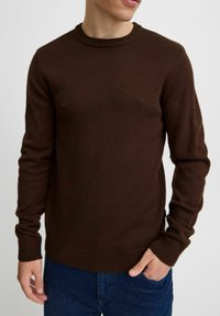 Brauner gestrickter Pullover mit einem gerippten runden Ausschnitt und Bündchen. Verfügt über eine schmale Passform und einen strukturierten Stoff mit einem dezenten Muster.