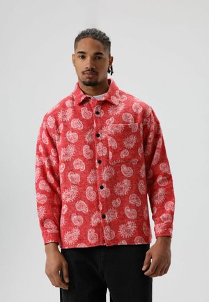 Rood hemd met patroon gemaakt van gestructureerde stof, met witte spiralen, een kraag, knopen aan de voorkant en een borstzakje.
