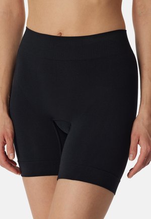 Femme portant un short de compression noir taille haute avec une pièce d'aisance à l'entrejambe, visible de la taille à mi-cuisse.